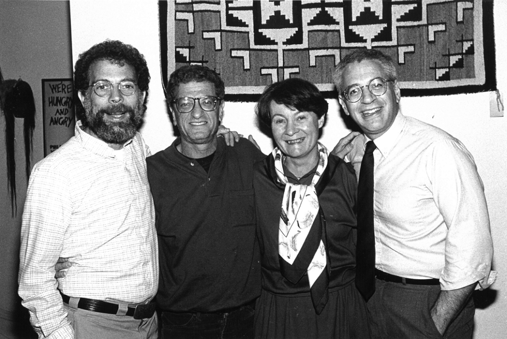 Black and white photo of four people standing and smiling